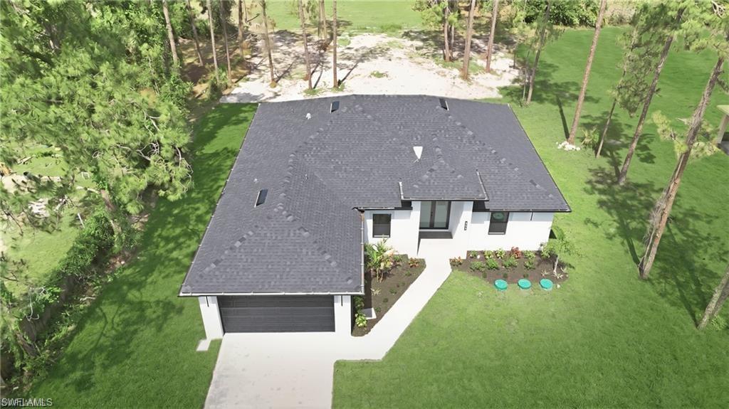 Modern residence with a dark shingle roof, white exterior, and an attached garage with a dark door
