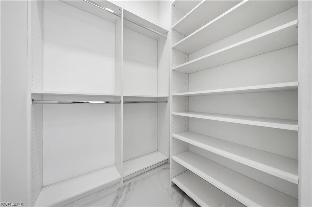 Custom closet system featuring white shelving and chrome hanging rods