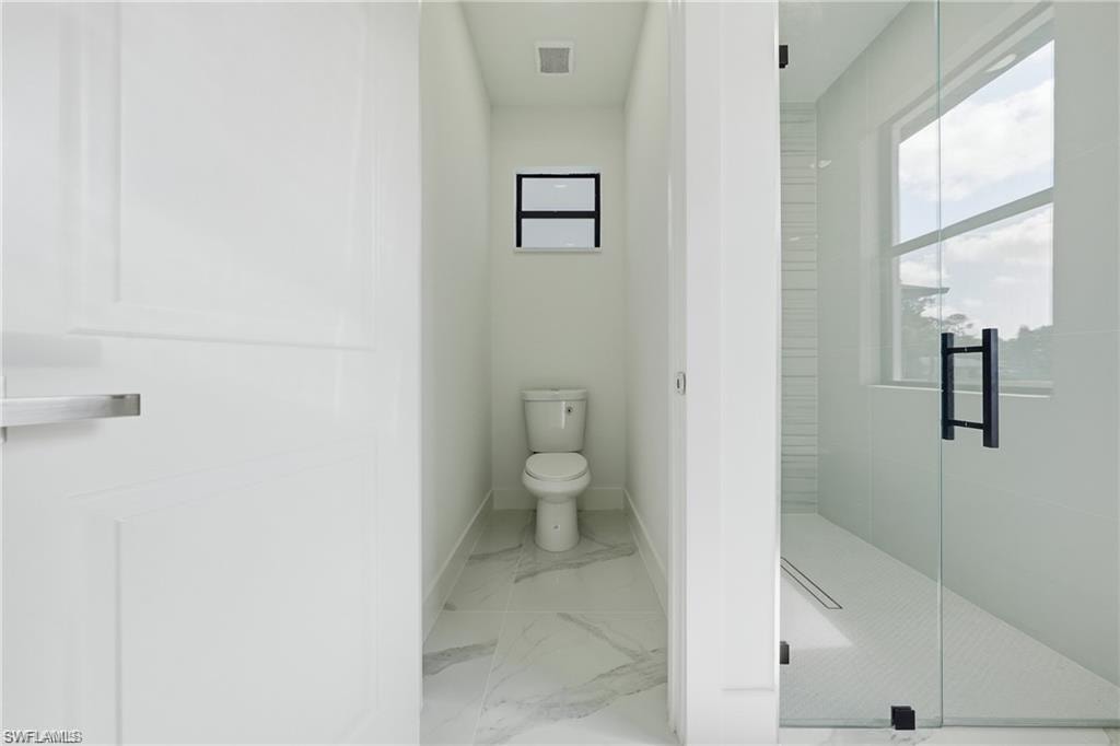 Enclosed water closet featuring a toilet and a window