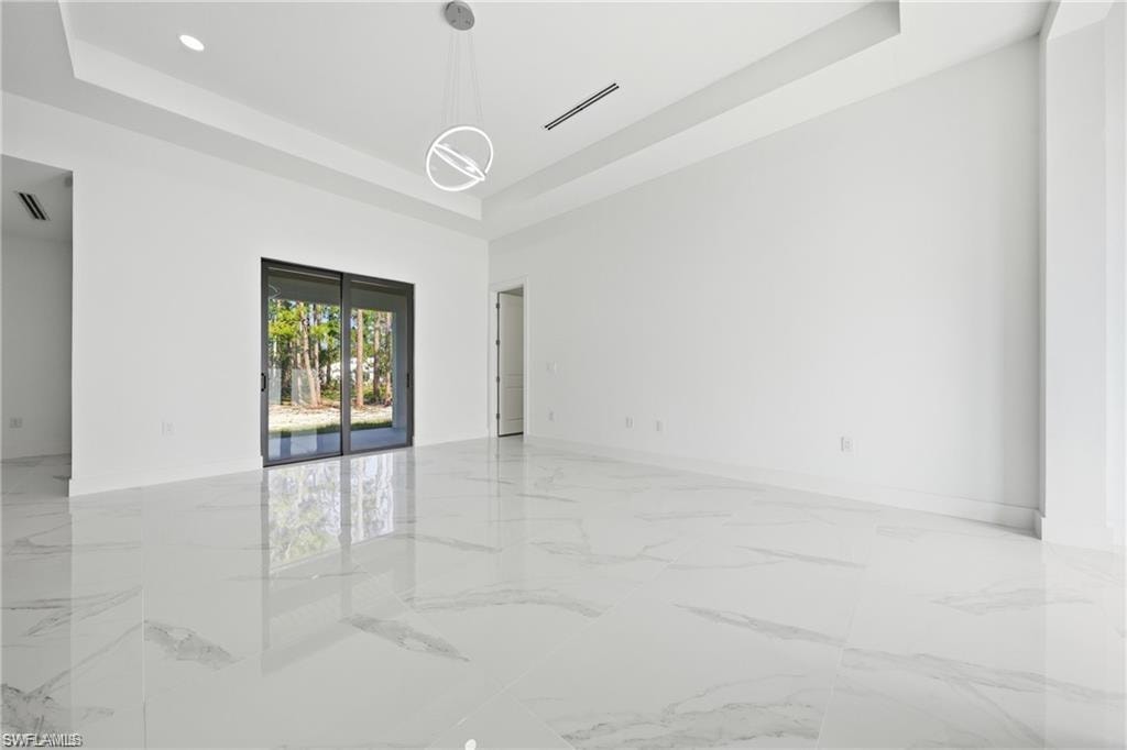 Spacious interior featuring large format tile flooring, a contemporary ceiling light fixture, recessed lighting, and a sliding glass door