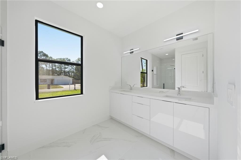 Dual vanity with integrated sinks, expansive mirror, linear lighting fixtures, and large black-framed window