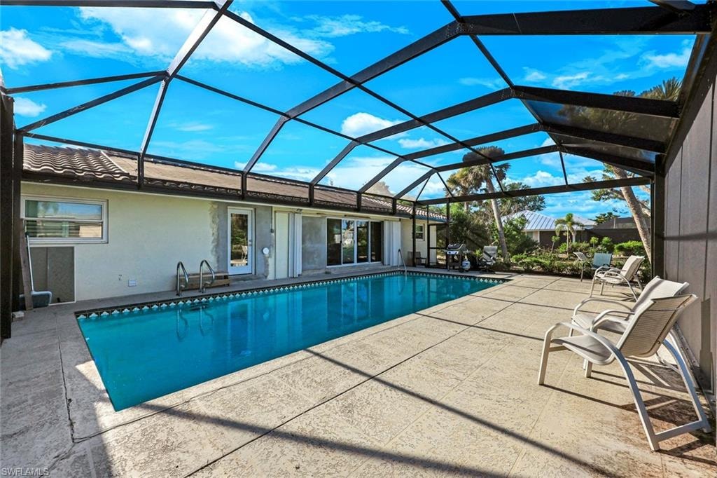 Screened-in swimming pool enclosure featuring a rectangular pool, concrete patio, and direct access to the interior via glass doors