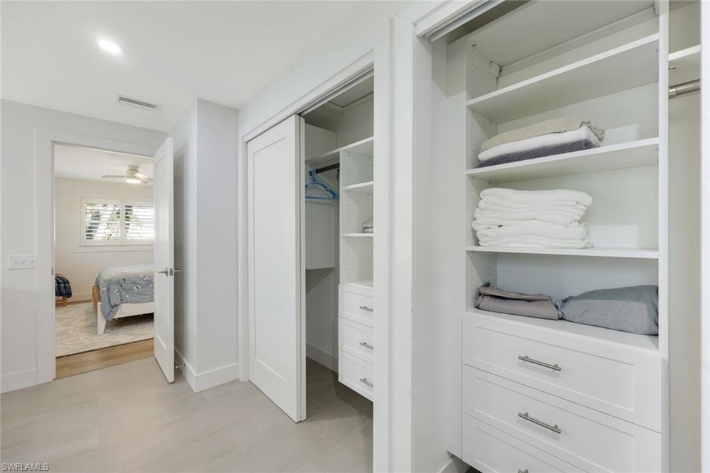 Custom closet organization system featuring white shelving and integrated drawers with brushed nickel hardware