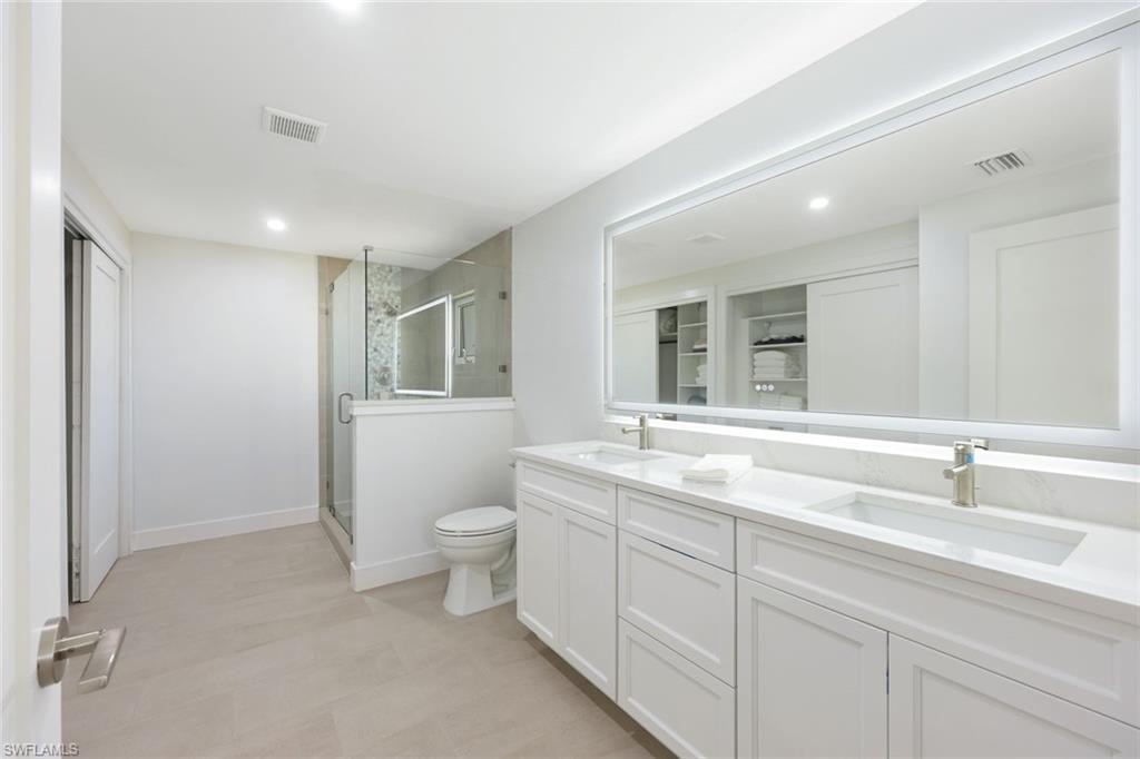 Bathroom featuring a double vanity with white cabinetry, integrated sinks, and brushed nickel fixtures