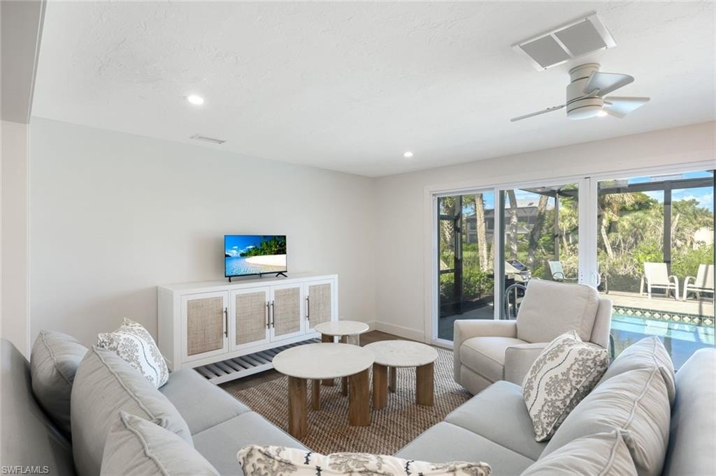 Living area featuring a ceiling-mounted fan, recessed lighting, and a white media console with woven cabinet fronts