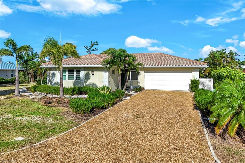 Single-story residence featuring a tile roof, light-colored stucco exterior, and a two-car garage
