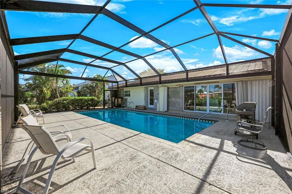 Resort-style pool enclosure featuring a sparkling in-ground swimming pool with lane markings, expansive stamped concrete decking, and a polycarbonate roof system providing protection while maximizing natural light