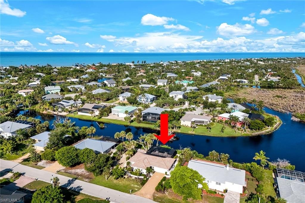 Waterfront property featuring a private boat dock, screened lanai, mature landscaping, and direct access to a canal system leading to the Gulf of Mexico