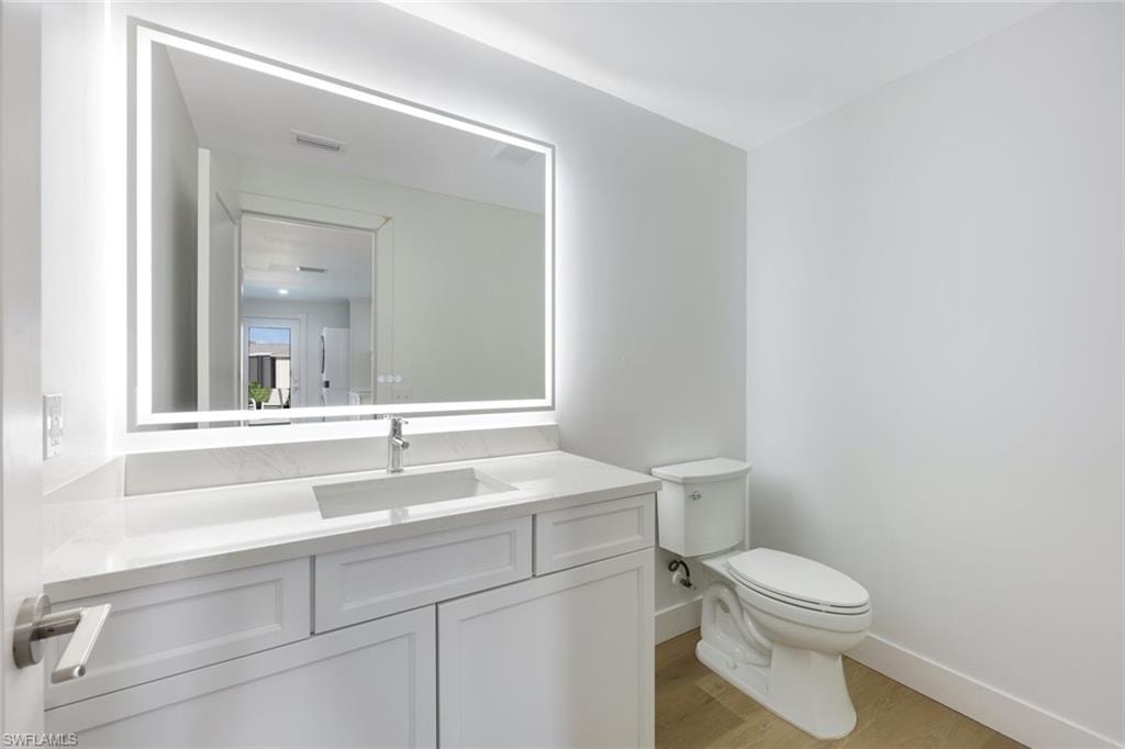 Modern bathroom featuring a vanity with a rectangular undermount sink, a chrome faucet, a white countertop, and integrated LED-lit mirror