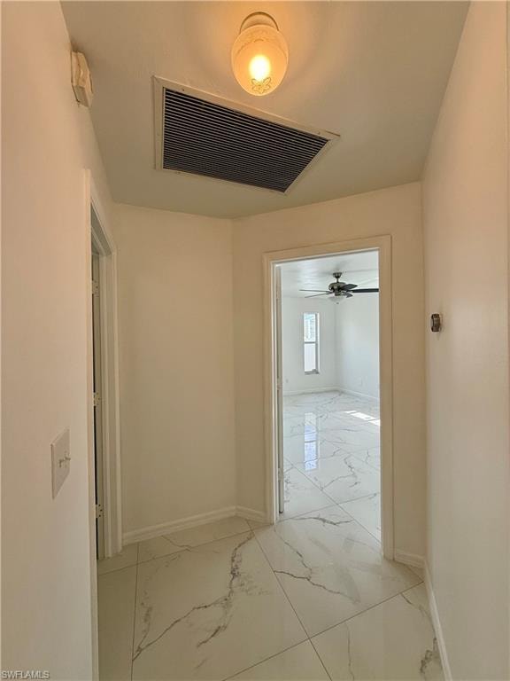 Hallway featuring white tile flooring with gray veining and bright white walls