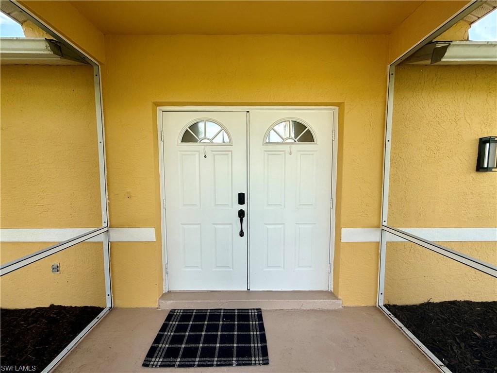 Dual panel entry doors featuring arched transom windows and stucco exterior finish