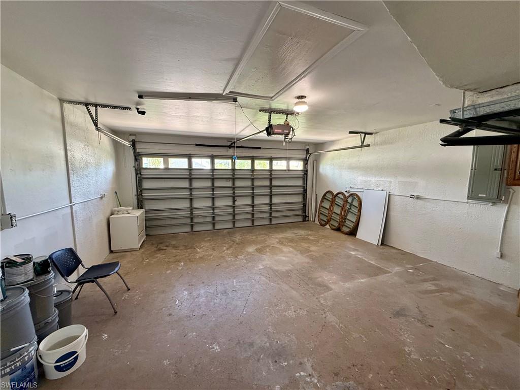 Garage interior with a roll-up door, overhead lighting, and an access panel