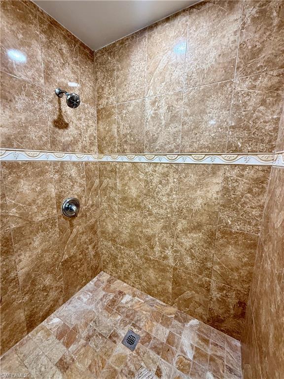 Spa-inspired shower enclosure featuring premium travertine tile throughout walls and floor, dual showerheads with chrome fixtures, and a decorative border accent strip