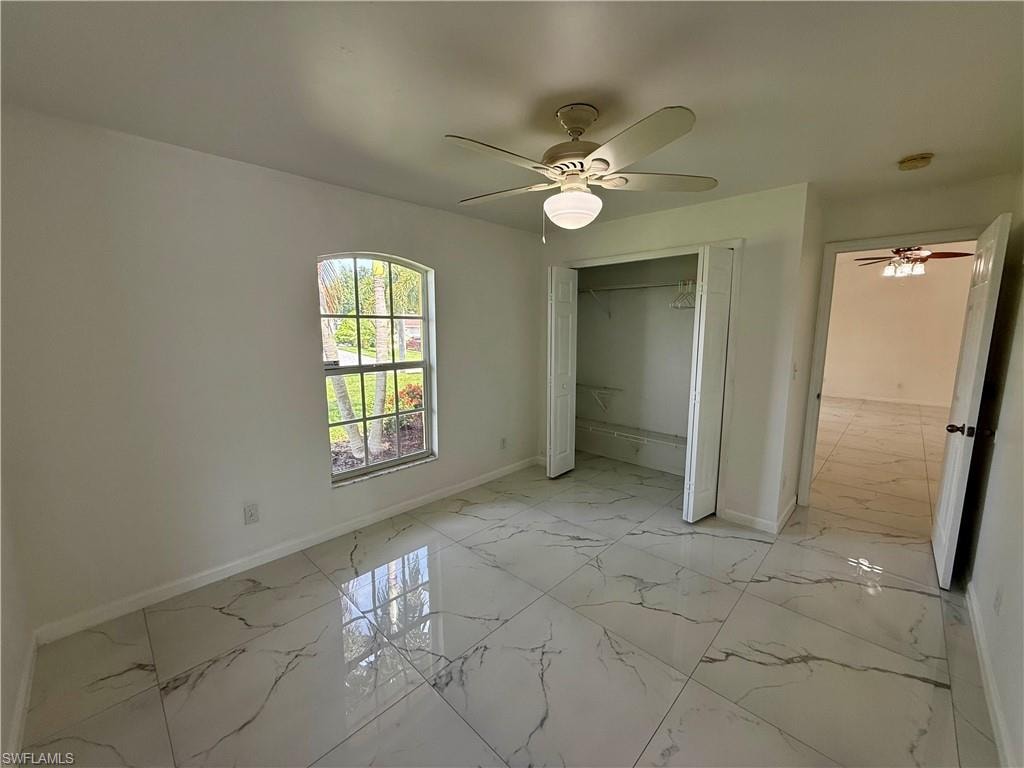 Spacious room featuring large format tile flooring, a rounded arched window, and a ceiling fan with integrated lighting