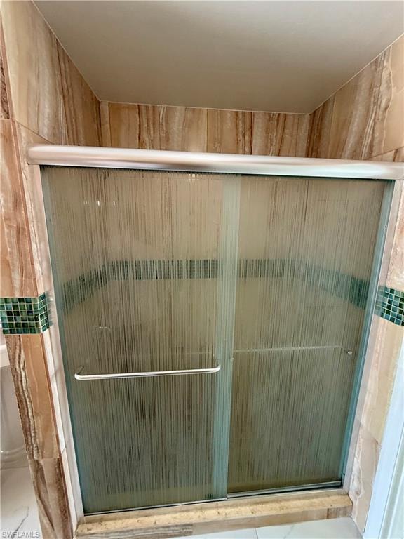 Shower enclosure with frosted sliding glass doors and a brushed metal handle