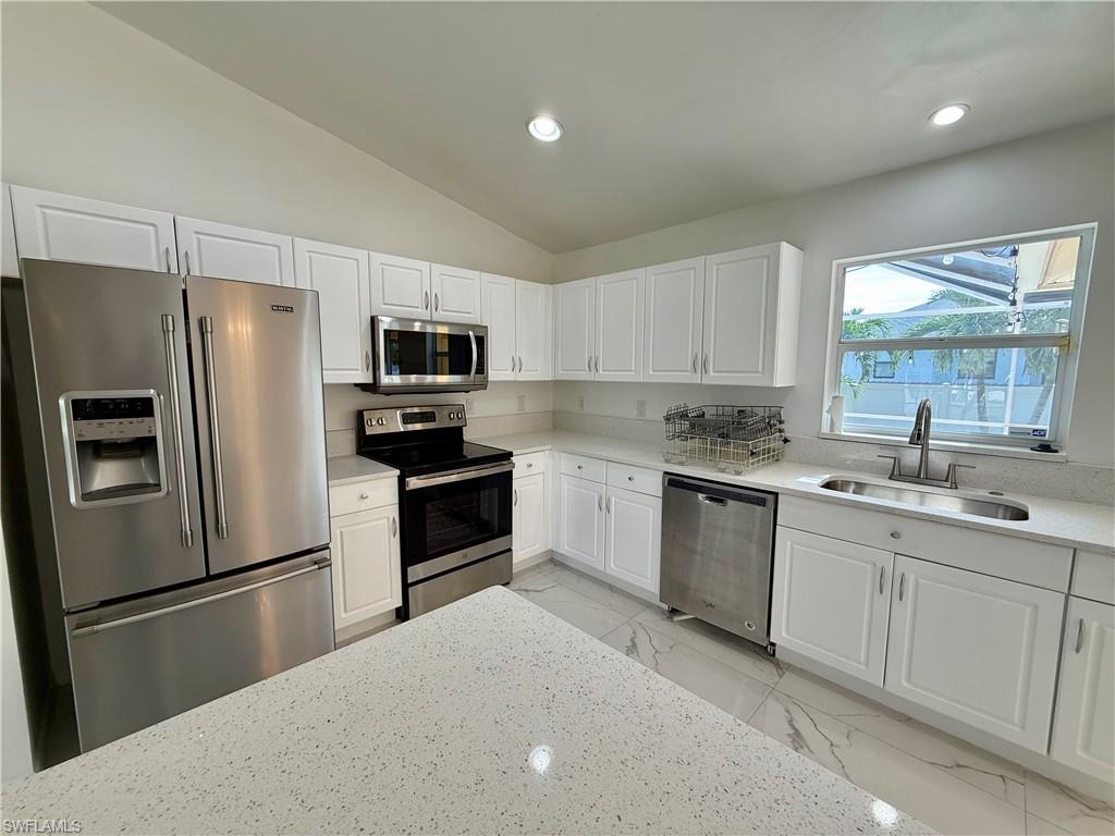Kitchen featuring white shaker-style cabinetry, stainless steel appliances, light-toned countertops, a stainless steel sink with a gooseneck faucet, and recessed lighting