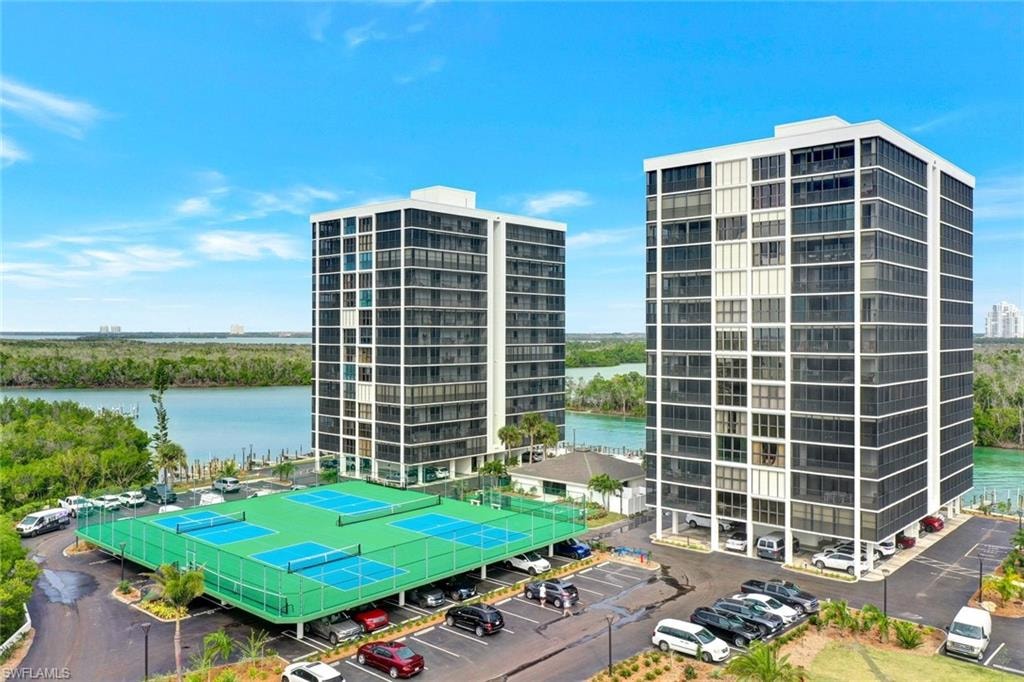 Twin high-rise towers with extensive glass balconies overlook a body of water and distant land