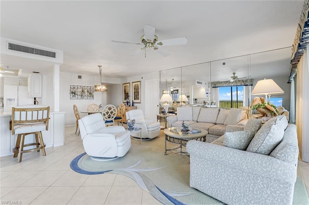 Open-concept living space featuring tiled flooring with an inlaid design, a built-in wall of mirrors, a ceiling fan, and recessed lighting