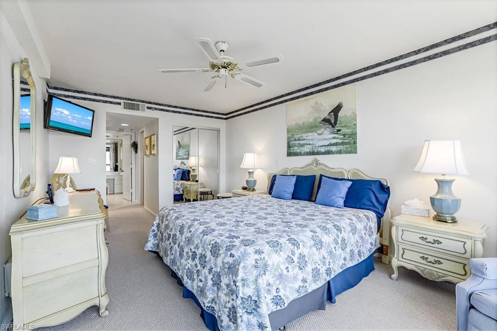 Carpeted bedroom featuring a ceiling fan, crown molding, and mirrored closet doors