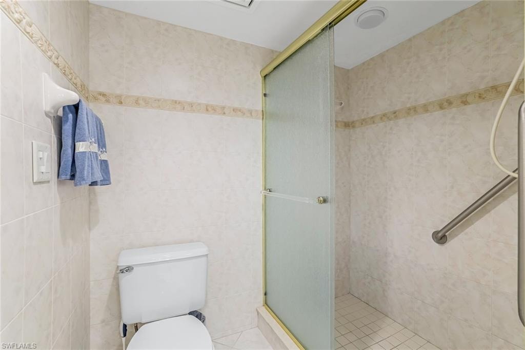 Tiled shower with frosted glass enclosure, gold-tone frame, and built-in grab bar