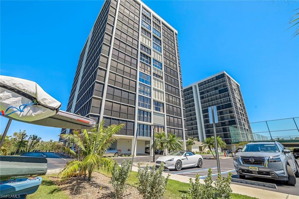 Modern high-rise residential building featuring extensive window-lines, clean architectural design, and a multi-level parking structure