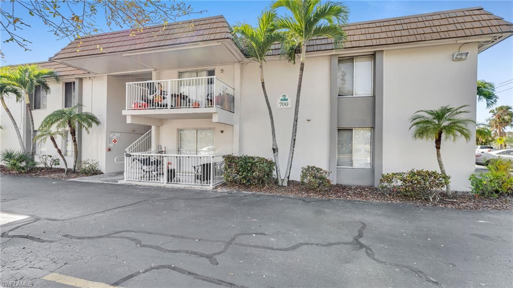 Two-story multi-unit building featuring a tan tile roof and balconies with white railings