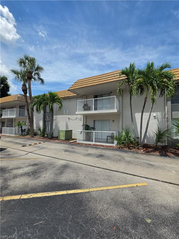 Two-story multi-unit building featuring a stucco exterior, tile roofing, and white balcony railings