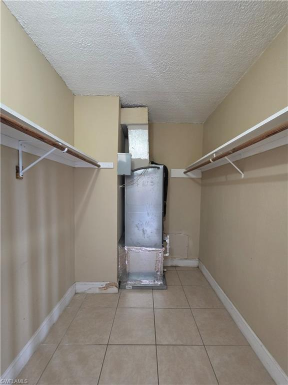 Utility closet with tiled flooring, neutral wall paint, and built-in shelving with hanging rods