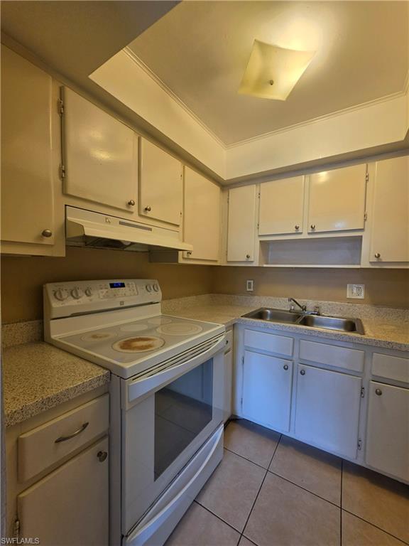 Kitchen featuring white cabinetry, a built-in range and oven, a stainless steel double sink, patterned countertops, and tile flooring