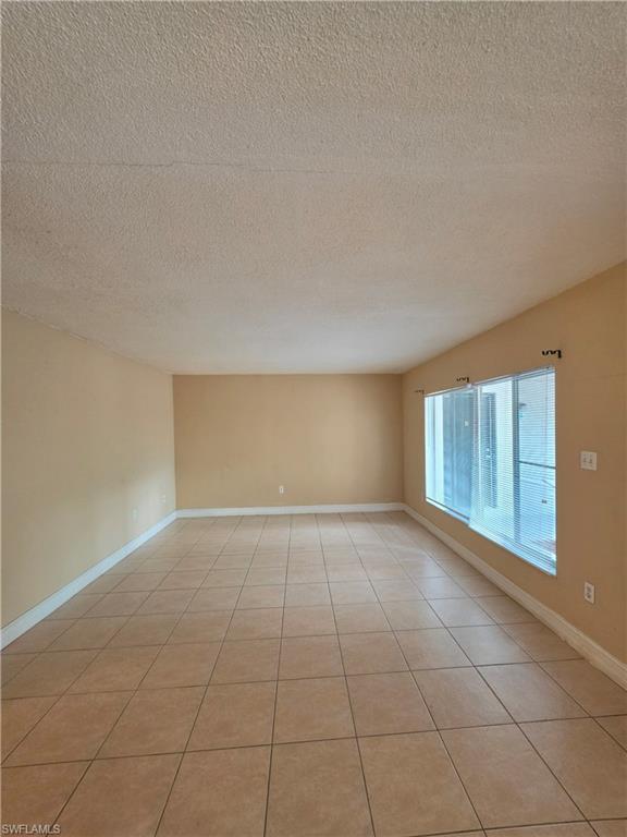 Spacious living area showcasing tile flooring throughout, abundant natural light from expansive sliding glass doors, neutral wall finishes, and an open floor plan with ample square footage for flexible furnishing arrangements