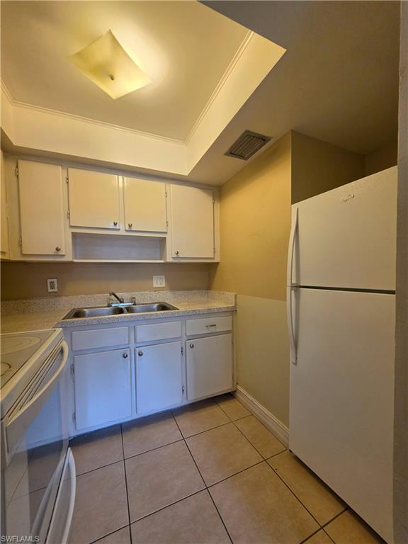 Kitchen featuring white cabinetry, a double basin sink, light-toned countertops, and tile flooring