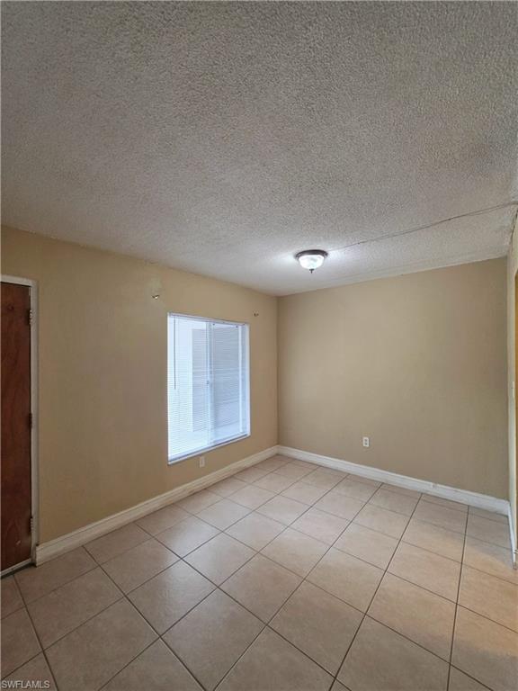 Spacious interior with neutral-toned walls, tile flooring, and a single window with horizontal blinds