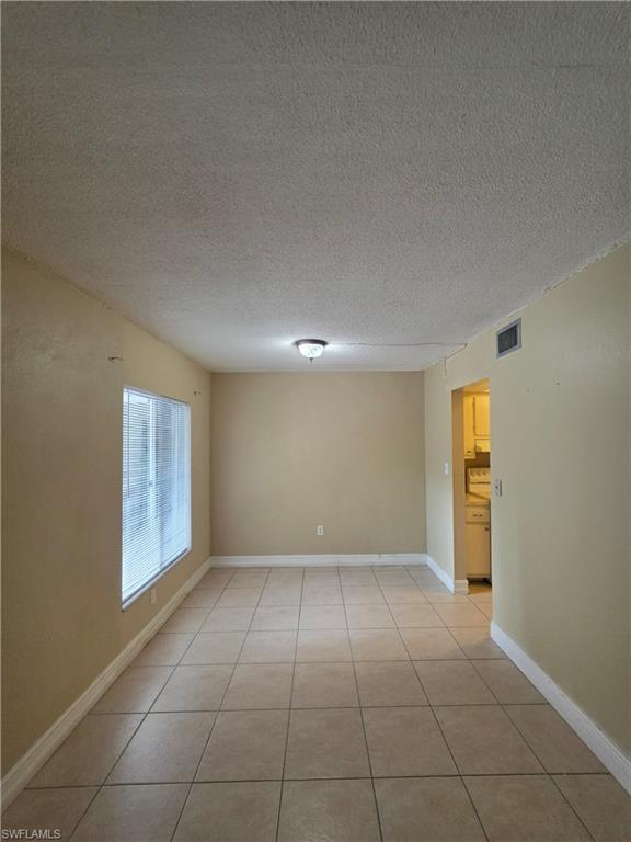 Spacious room featuring tile flooring, neutral wall paint, and a large window with horizontal blinds