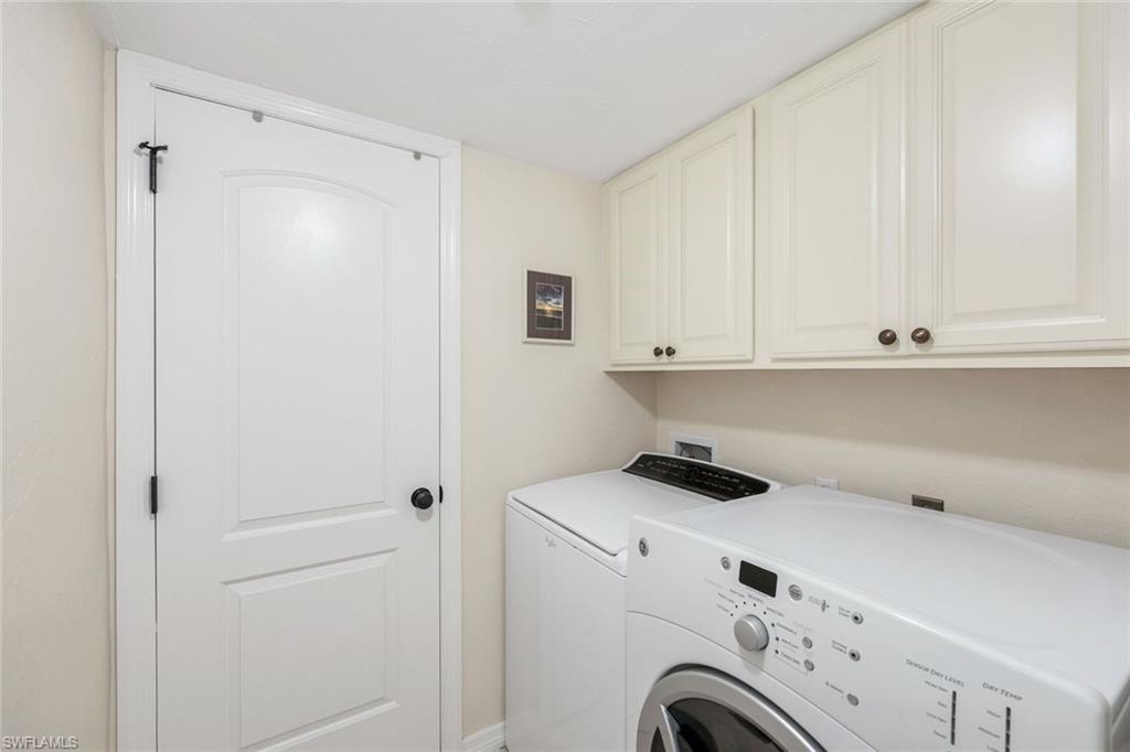 Laundry area featuring upper cabinetry with bronze hardware, a light-colored countertop, and a white paneled door with black hardware