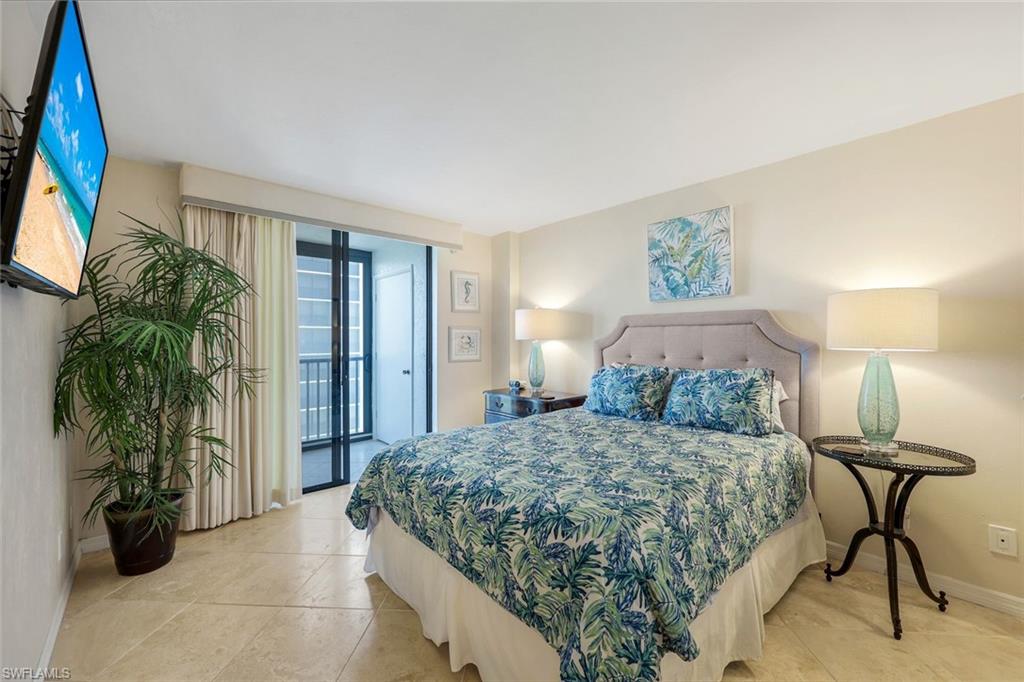 Bedroom featuring neutral-toned walls, tile flooring, and a large glass sliding door with balcony access