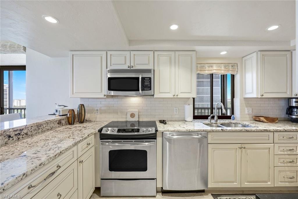 Kitchen featuring light-toned cabinetry, granite countertops, stainless steel appliances, a subway tile backsplash, and recessed lighting