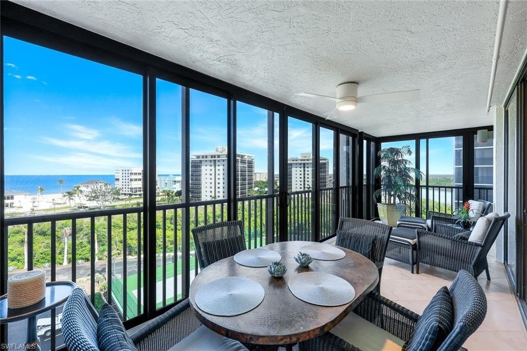 Enclosed balcony featuring floor-to-ceiling windows, a ceiling fan, and tile flooring