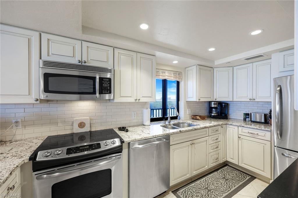 Kitchen featuring white cabinetry, granite-finish countertops, stainless steel appliances, a subway tile backsplash, and recessed lighting