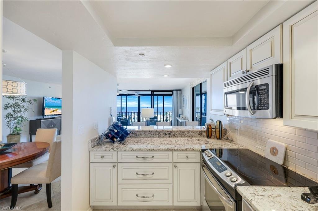 Kitchen featuring white cabinetry, granite countertops, a built-in microwave, and a subway tile backsplash