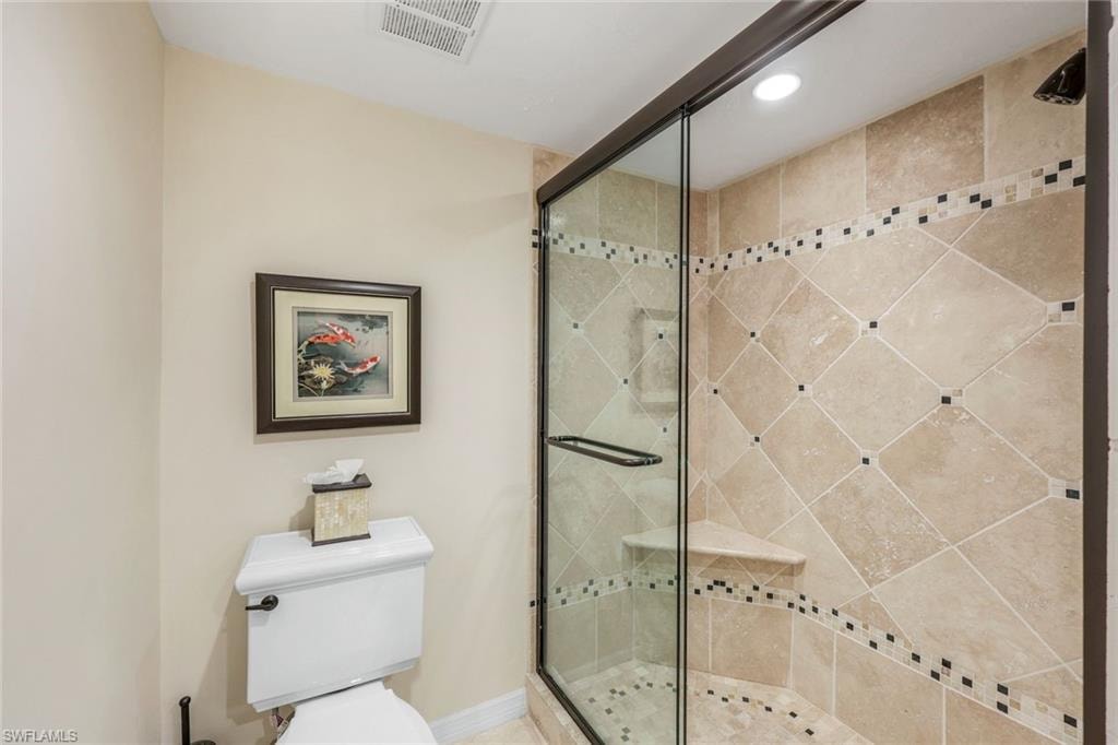 Walk-in shower with clear glass enclosure and dark bronze framing