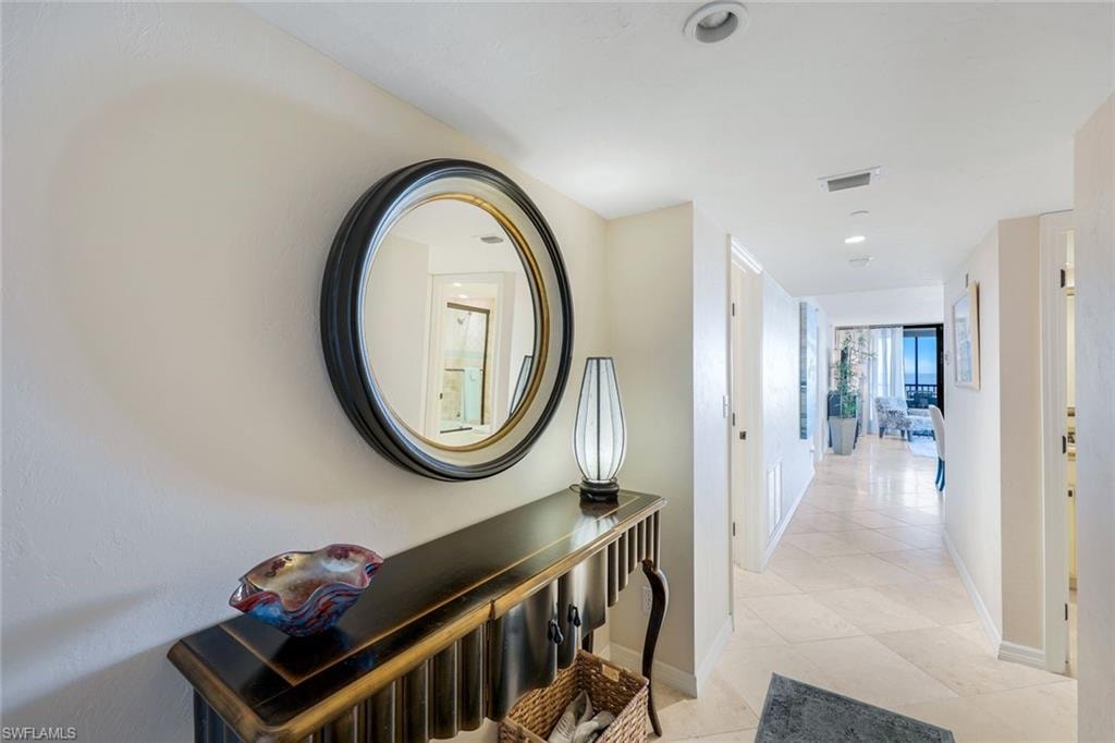 Hallway featuring light-toned walls, recessed lighting, and cream-colored tile flooring