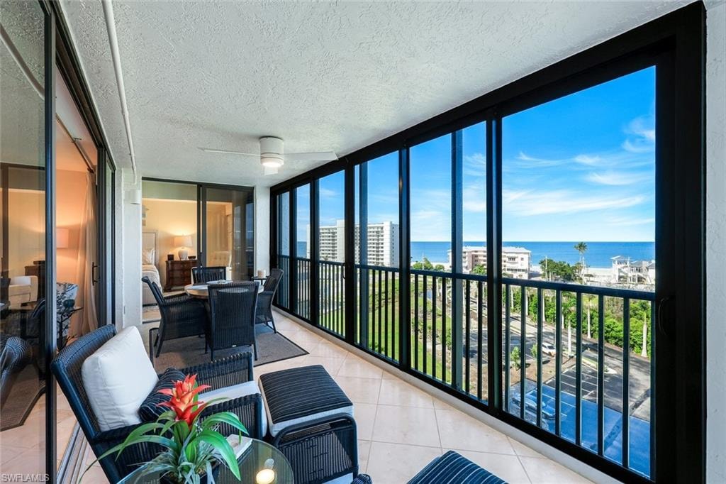 Enclosed balcony featuring floor-to-ceiling windows, tile flooring, a ceiling fan, and sliding glass doors