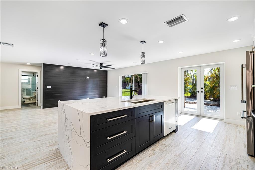 Modern kitchen featuring a striking black cabinetry island with white quartz countertop, stainless steel appliances, and chrome hardware