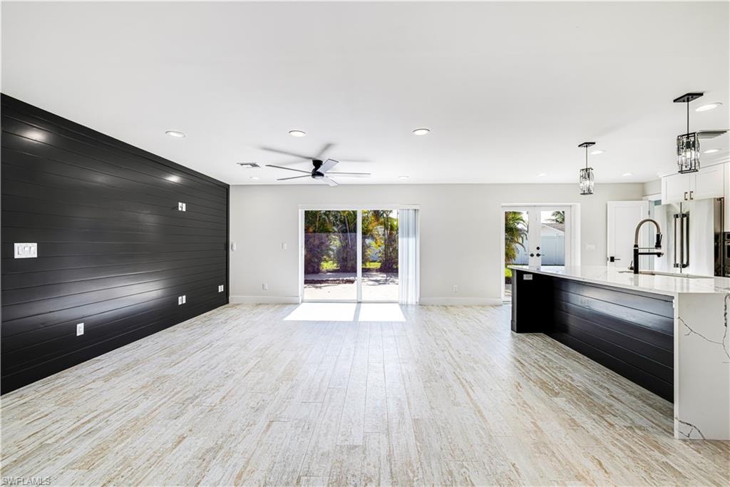 Open-concept living area with light wood-finish flooring, recessed lighting, and a modern ceiling fan