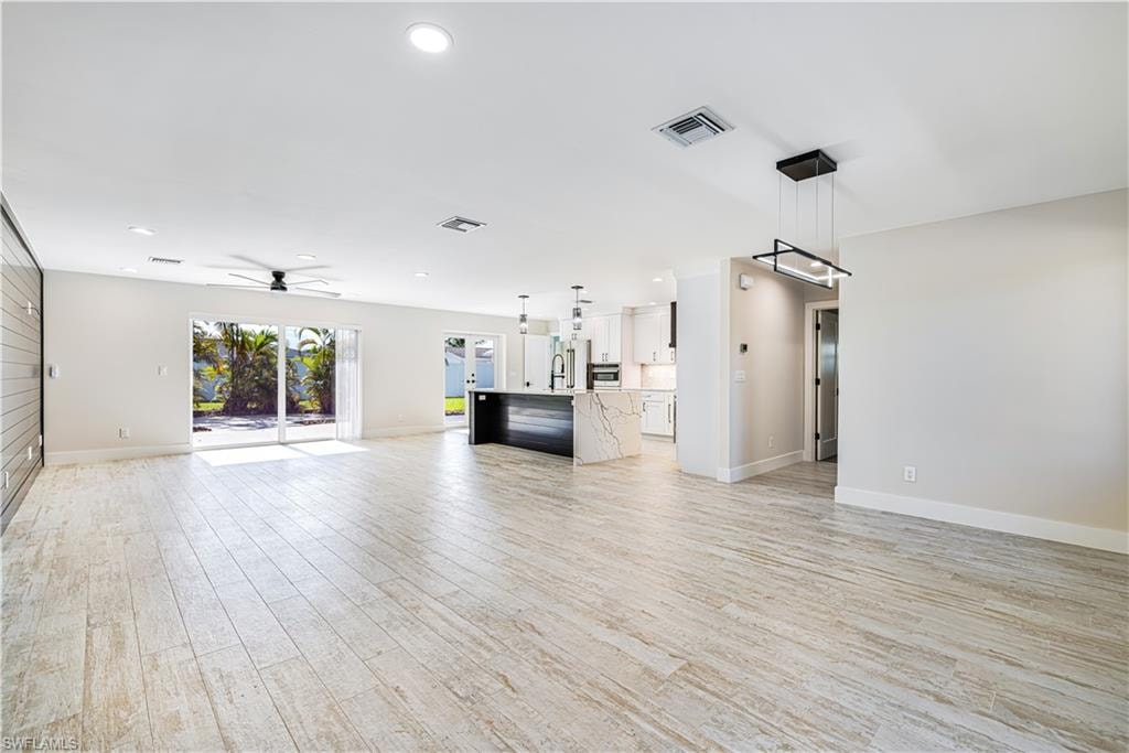 Open-concept living area featuring wood-finish plank flooring, recessed ceiling lighting, and a modern chandelier