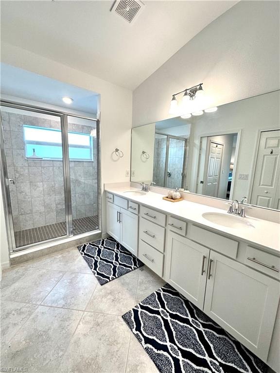 Bathroom with tile floors, dual sinks, a shower with shower door, and large vanity