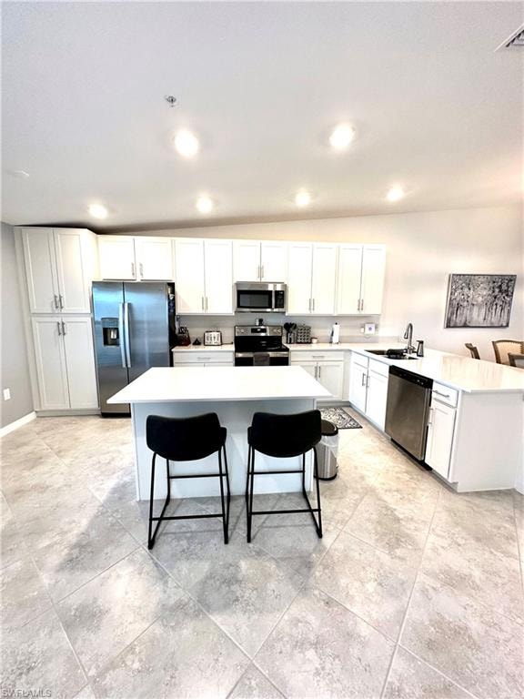 Kitchen with a breakfast bar, sink, light tile floors, and stainless steel appliances