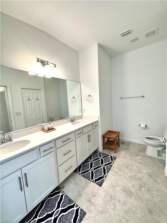 Bathroom with tile flooring, toilet, and double sink vanity