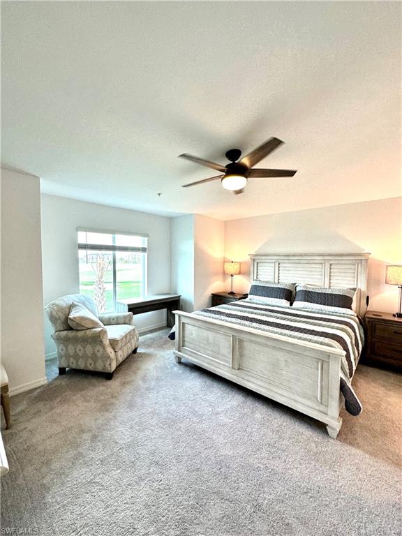 Bedroom with a textured ceiling, carpet flooring, and ceiling fan