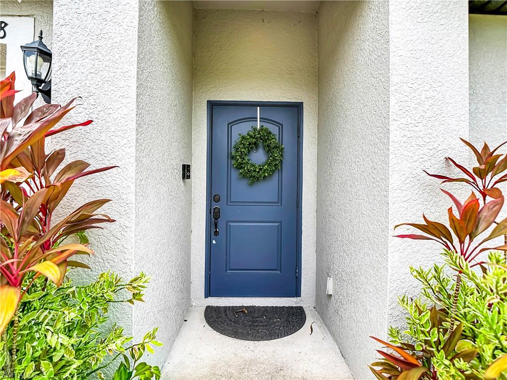 Entryway featuring a paneled navy blue door, textured white exterior walls, and a wall-mounted light fixture
